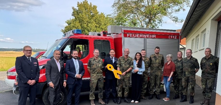 Vor einem Einsatzwagen der Feuerwehr stehen von links nach rechts; Gemeindebrandinspektor Gemeinde Willingshausen Ralf Lipphardt, stellv. Vorsitzender FöV Stab DSK Marcello Camerin, Bgm Willingshausen Luca Fritsch, Verteter DSK Oberstarzt Dr. Oliver Behr, Ortsvorsteher Zella Jan-Henrik Ebers, Vorsitzender FöV Stab DSK Hauptmann Martin Würz, Mitglied des hessischen Landtags Christin Ziegler, Stellv. Ortsvorsteher u. Angehöriger Jägerbataillon 1 Oberfeldwebel Tim Friedrich, Angehöriger DSK Major Tobias Ratajzcak, Beiratsmitglied FöV Stab DSK Marion Fenner, Vorsitzender RK Zella Obergefreiter d.R. Matthias Hett, stv. Vorsitzender RK Zella Hauptfeldwebel d.R Karsten Friedrich. , BwK Koblenz Oberstarzt d.R. Dr. Frank Hellmann; In der mitte befindet sich die gelbe Schleife