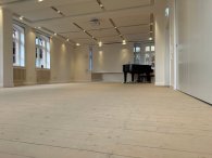 Seminarraum ein leerer Raum mit Holzdielen und einem Klavier im Hintergrund